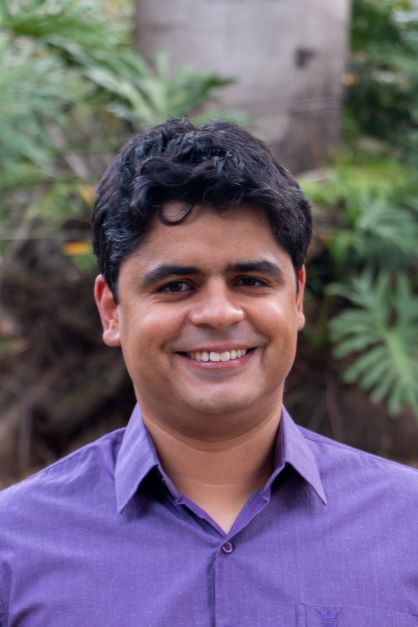 A smiling man in a purple button-up shirt