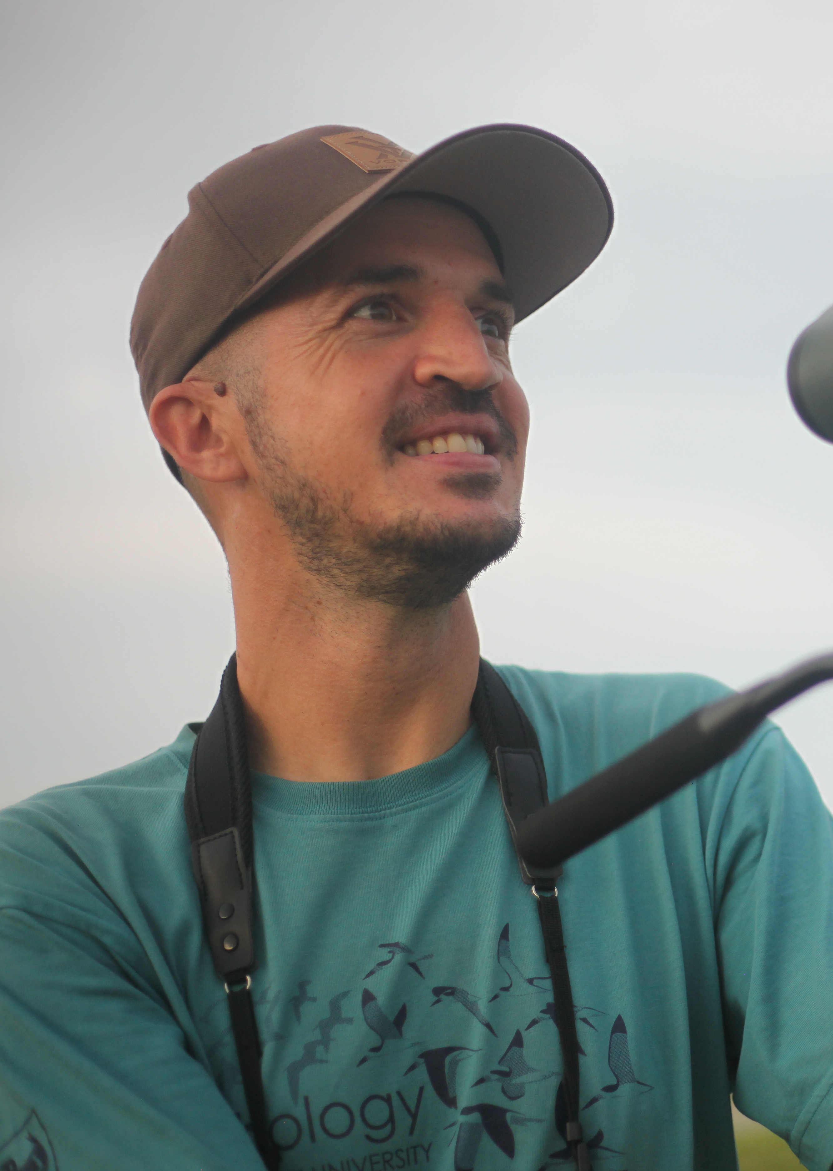 A man wearing a cap and green shirt